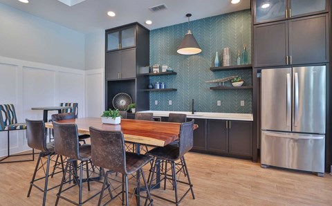 A kitchen with a table and chairs in the foreground and a refrigerator in the background.