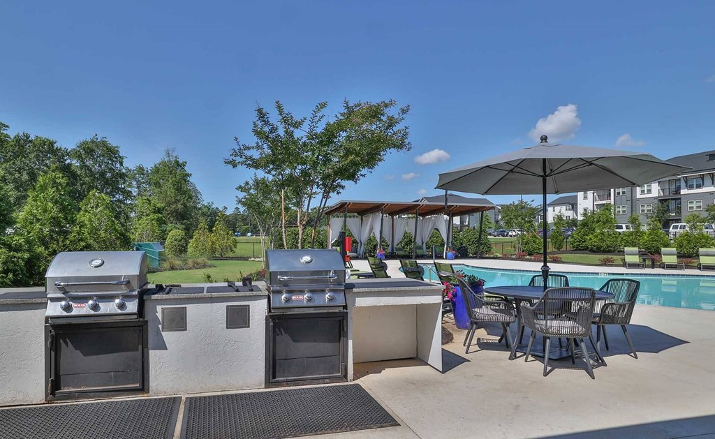 A patio with a grill, table, and chairs.