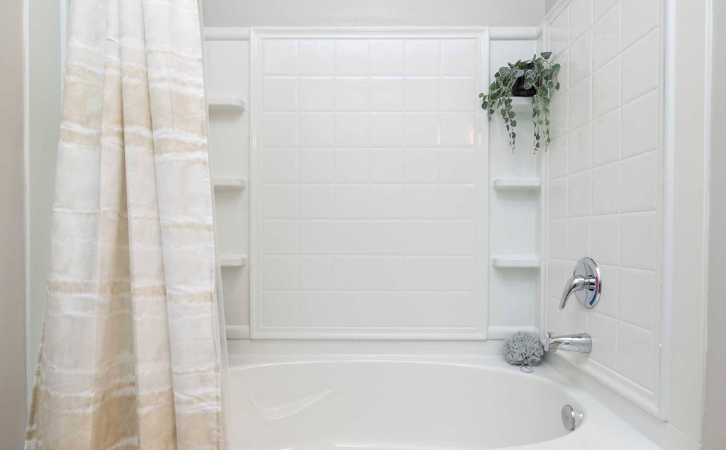 A white bathroom with a white tub and a white shower.