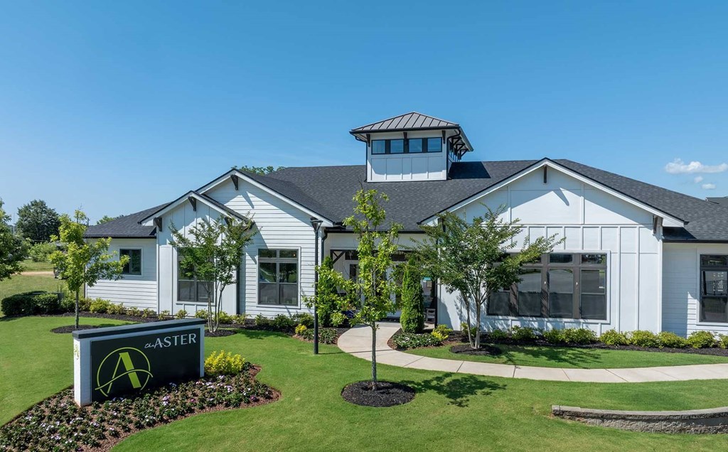 A white building with a black sign that says "ASTER" in front of it.