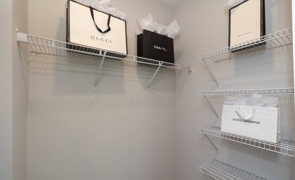 Three bags with Gucci, Chanel, and Dolce & Gabbana logos are displayed on shelves.