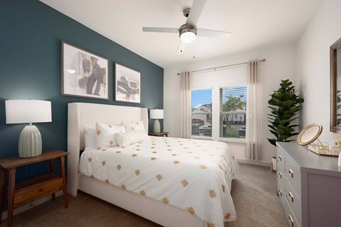 A bedroom with a bed, nightstand, and a ceiling fan.