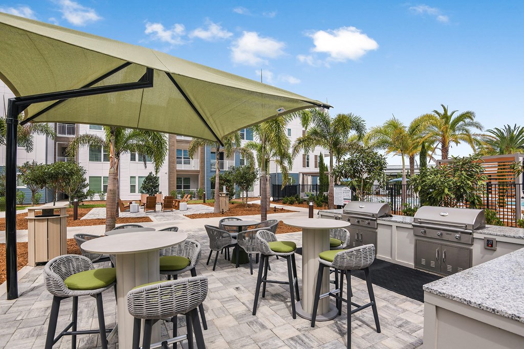 a patio with tables and chairs and a grill