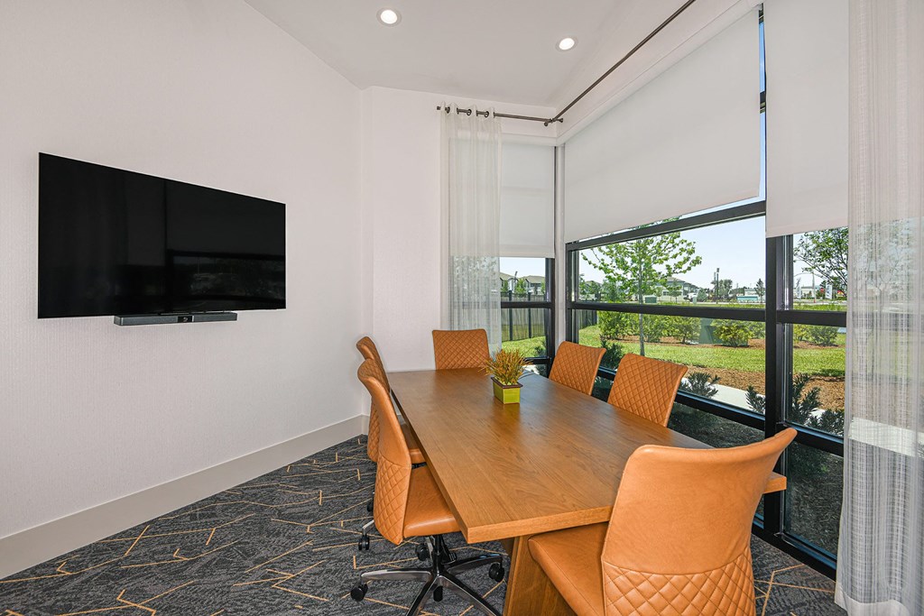 a conference room with a table and chairs and a tv on the wall