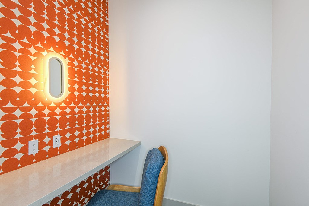 a chair in front of a orange wall with a small window