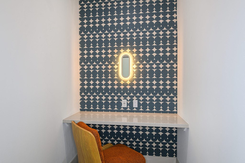 a small desk with a chair in front of a wall with a patterned wallpaper and a