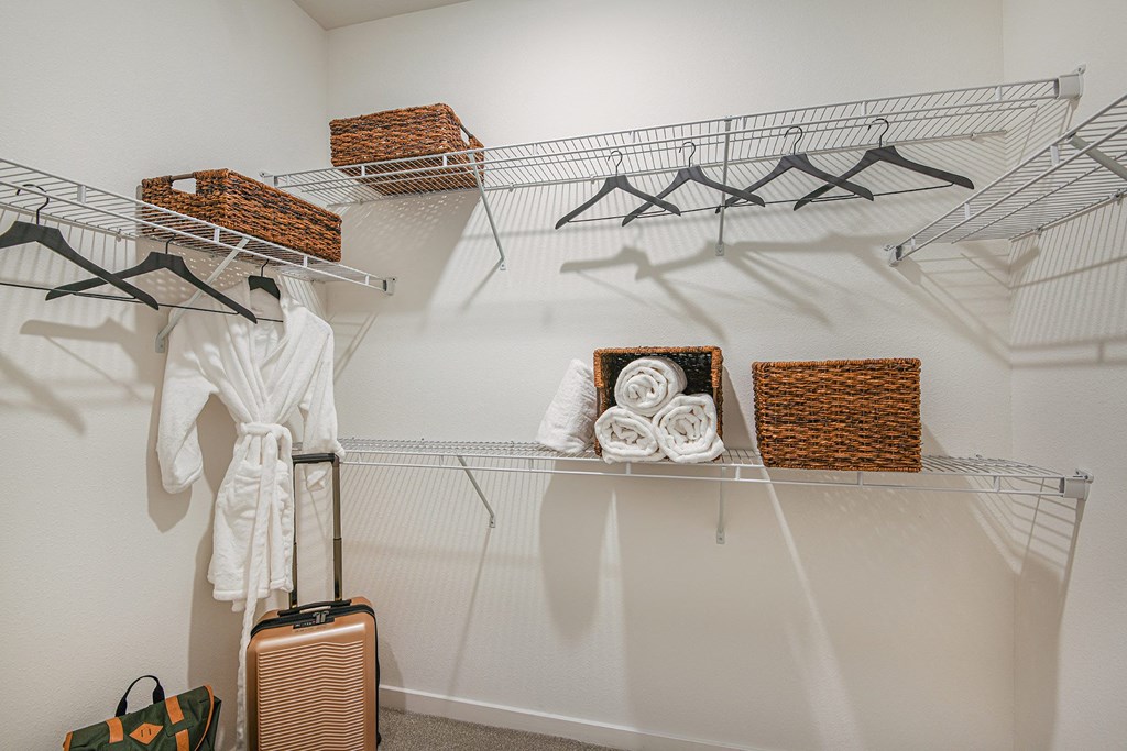 a walk in closet with a white robe and wicker baskets