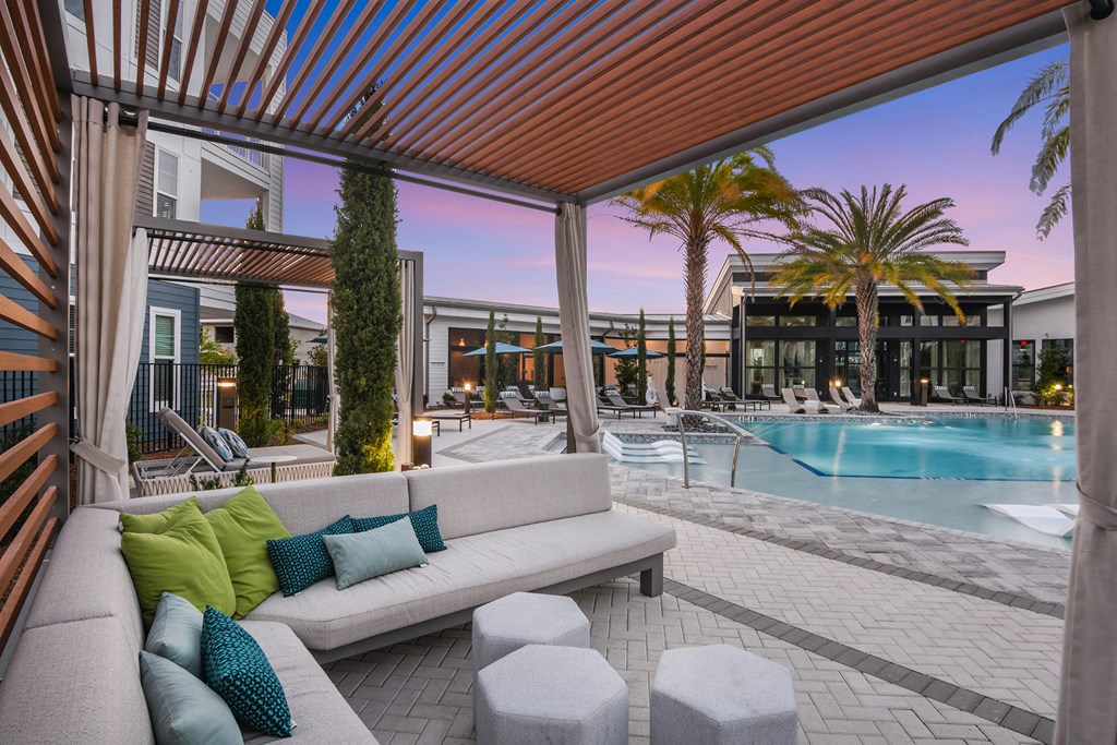a patio with a couch and chairs and a pool in the background
