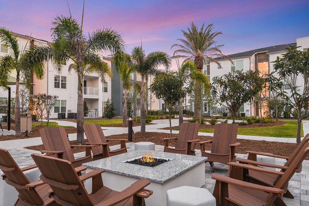 a patio with a fire pit and chairs