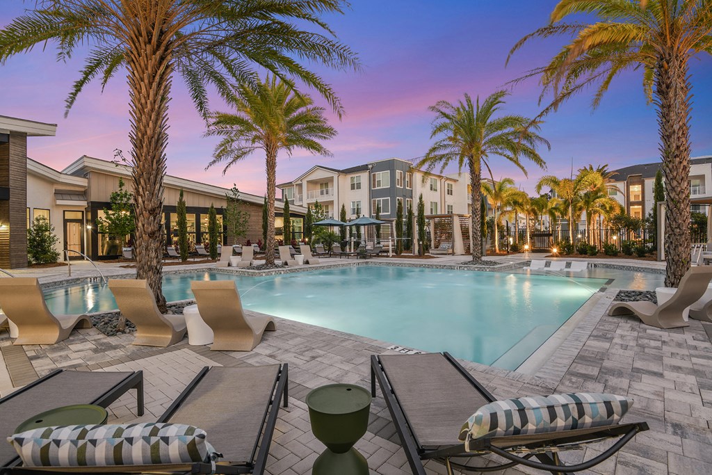 a swimming pool with chaise lounge chairs and palm trees