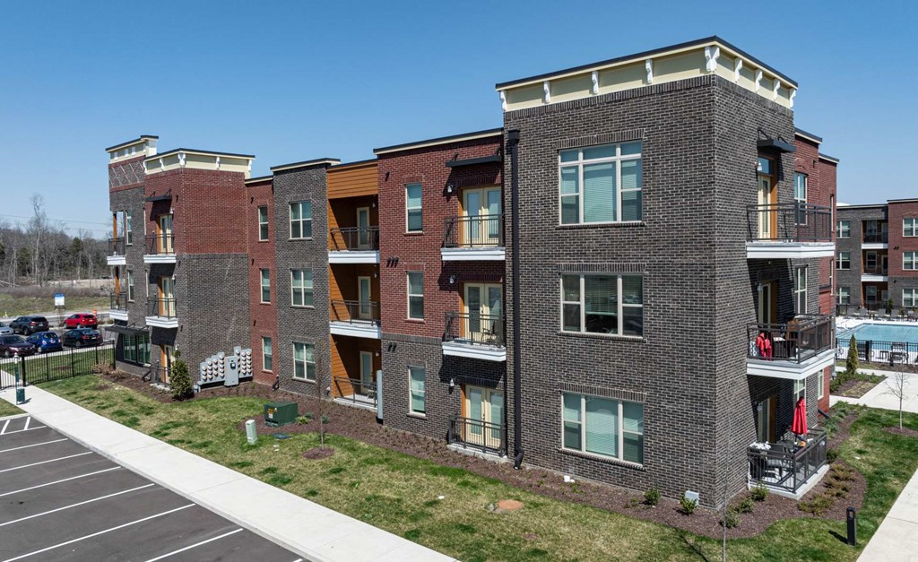 A large apartment complex with a parking lot in front.