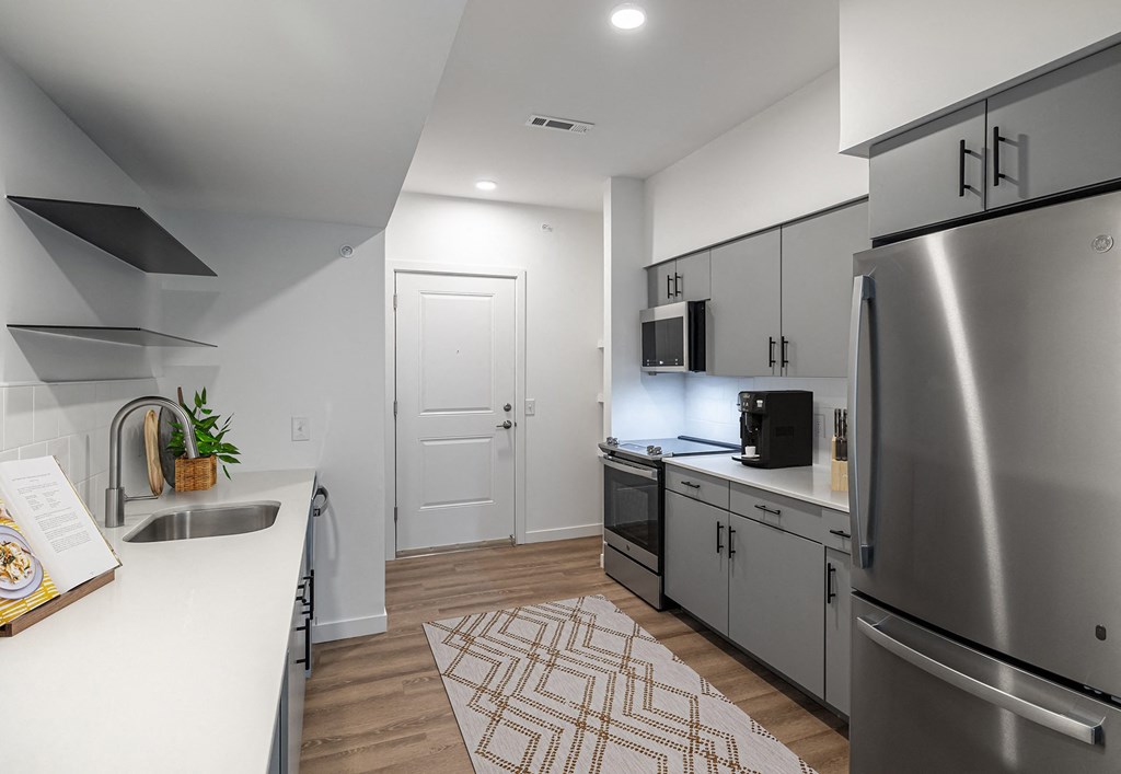 an open kitchen with stainless steel appliances and white countertops