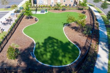 A playground with a green surface and a black fence.