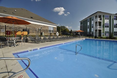 1-Bedroom Apartments in Wyoming, MI - The Haven - Large Heated Outdoor Saltwater Swimming Pool Surrounded by Lounge Chairs and Umbrellas, Enclosed with a Fence, and Overlooking the Apartments.