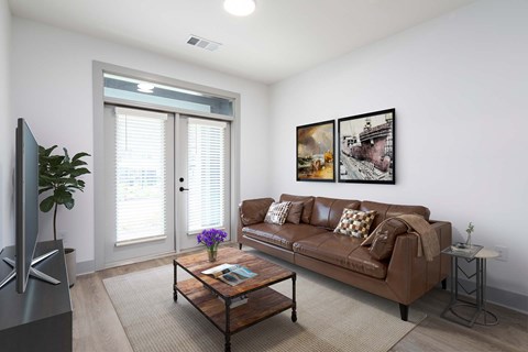 A living room with a brown couch, a coffee table, and a flat screen TV.