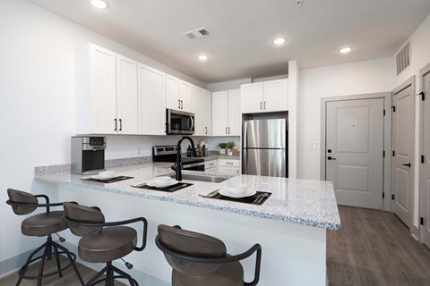 A kitchen with a white countertop and brown barstools.