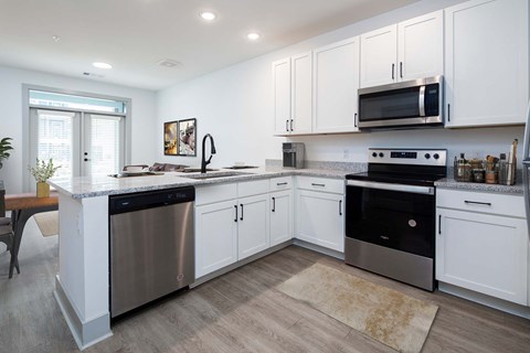 A modern kitchen with white cabinets and stainless steel appliances.