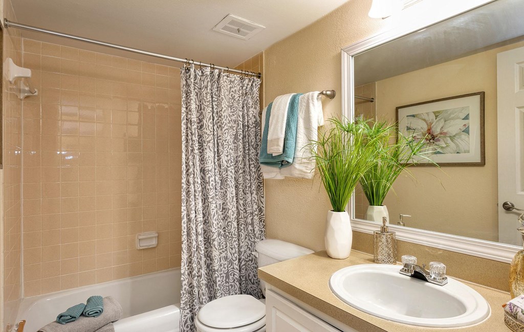 A bathroom with a white toilet, a white sink, and a shower with a curtain at Legacy, Tampa, FL, 33603