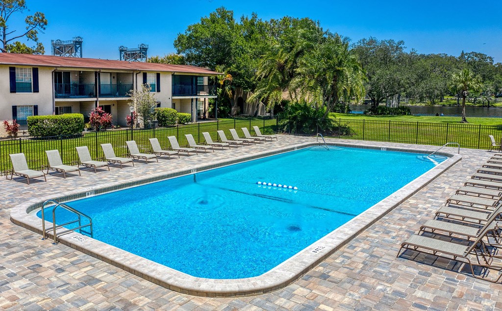 A swimming pool surrounded by lounge chairs and trees at Legacy, Tampa, FL, 33603