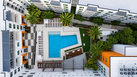 A modern apartment complex with a pool and palm trees.