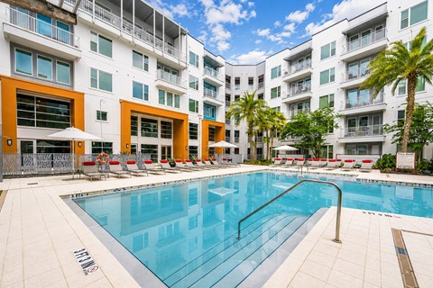 A swimming pool in front of a white and orange building.