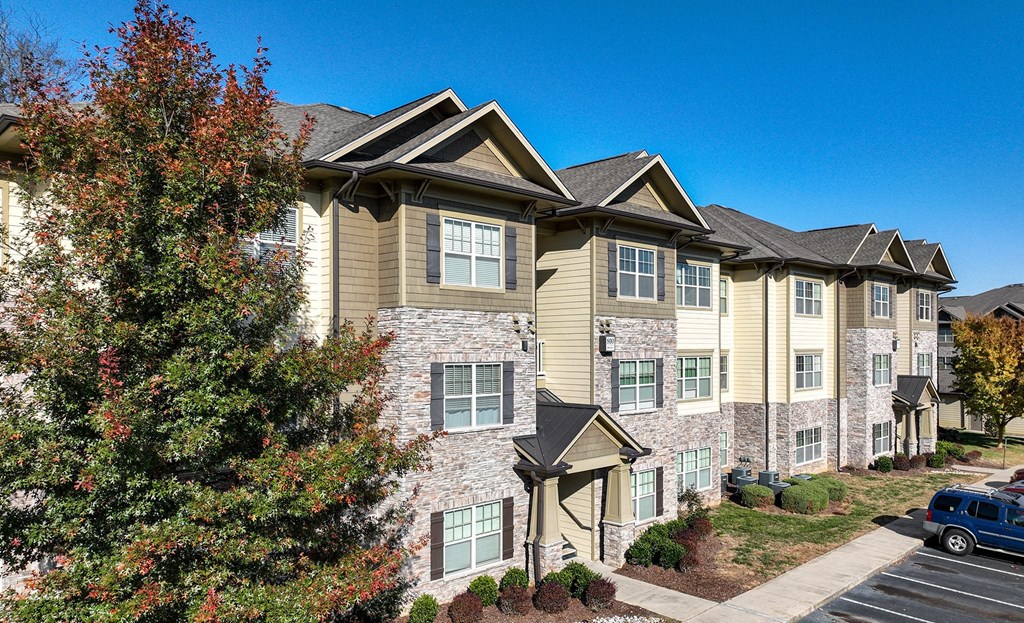 an apartment building with brick and stone exterior and trees