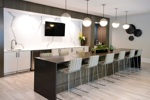 a kitchen with a long island with chairs and a tv