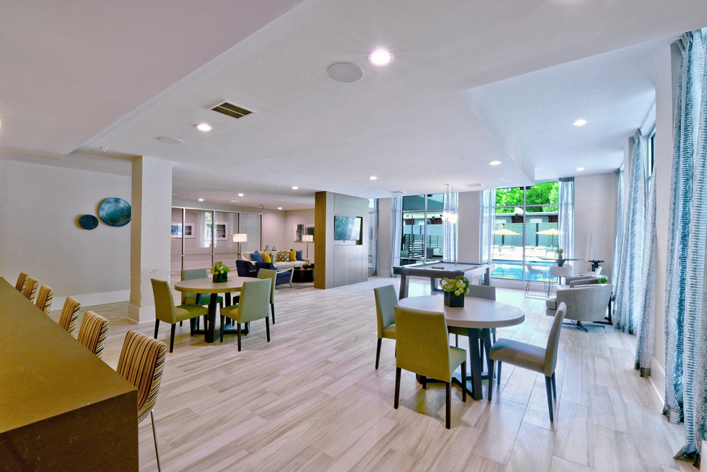 a communal area with tables and chairs and a living room with a pool