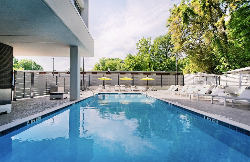 a swimming pool with chairs and umbrellas next to a building