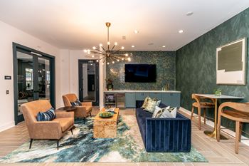 A living room with a blue rug and a chandelier.