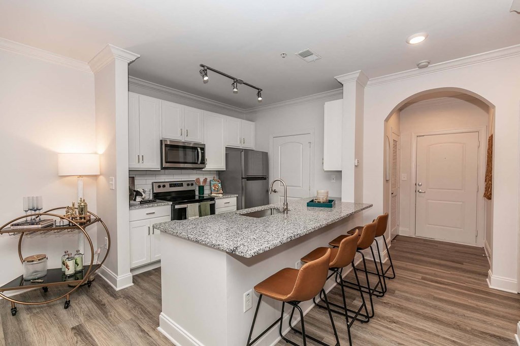 Two-Bedroom Apartments in Newnan, GA - The Jackson - Kitchen with Hardwood-Style Flooring, Customized Cabinetry, Stainless Steel Appliances, Kitchen Island, and Bar Stools.