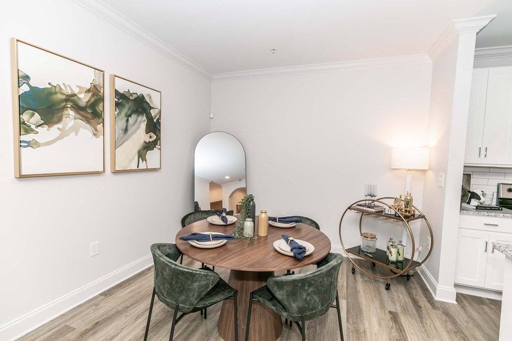 1-Bedroom Apartments in Newnan, GA - The Jackson - Dining Room with a Wooden Dining Table, 4 Chairs, Mirror, Wall Art, Lamp, and a Deco Bar Cart.