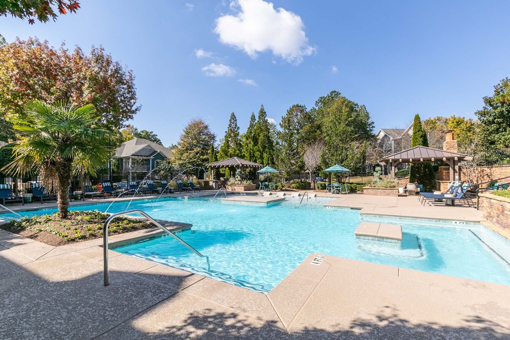 a swimming pool with trees and umbrellas at the resort