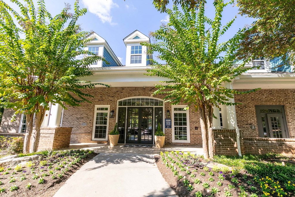 the front entrance of a brick building with trees and a sidewalk