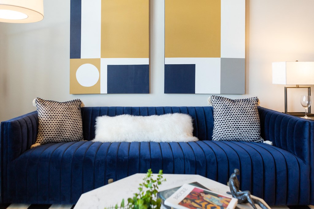 a living room with a blue couch and paintings on the wall