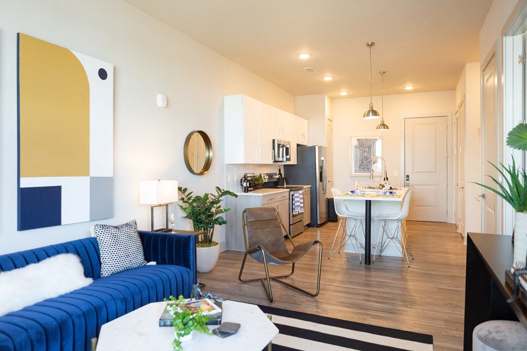 a living room and kitchen with a blue couch and a table