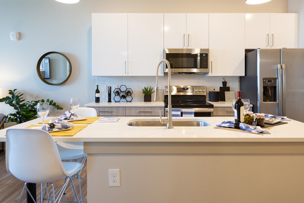 a kitchen with a sink and a counter top and a stainless steel refrigerator