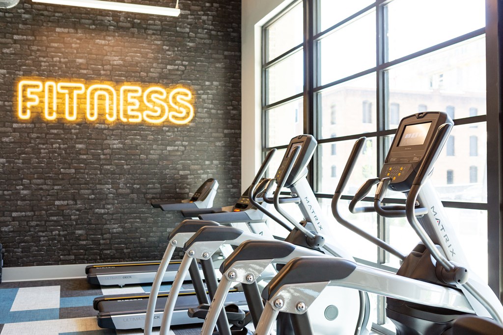 a gym with treadmills and weights in front of a window