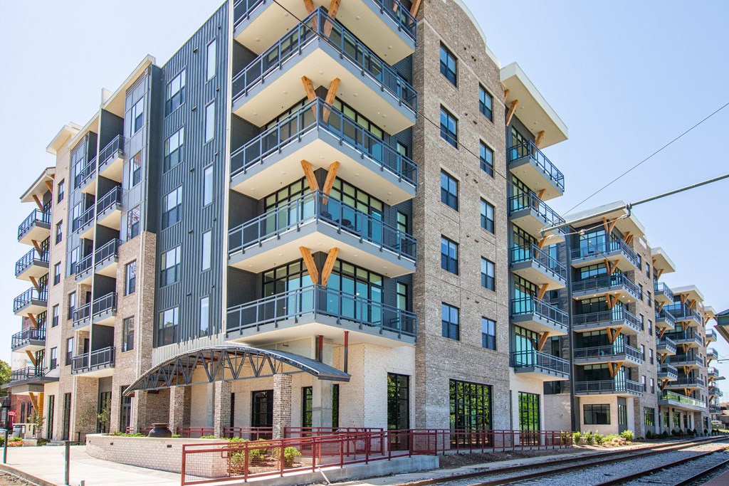 Pet Friendly Apartments in Downtown Memphis TN - The Landing Residences - Corner Street View of Buidling Beside Trolley Tracks with Stone and Grey Details, and Showcasing Balconies