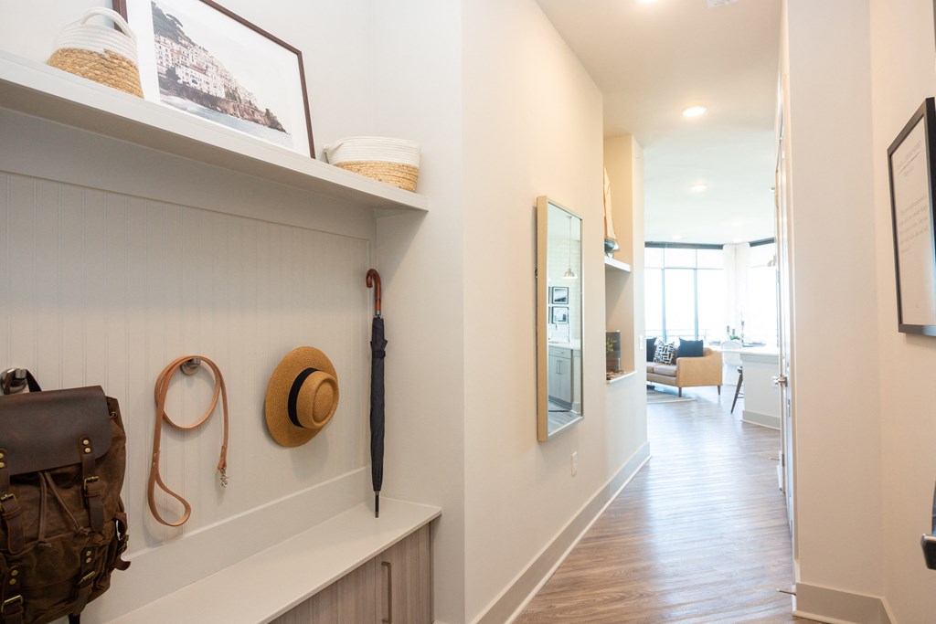 a hallway with a backpack and hat on a wall and a mirror on a shelf