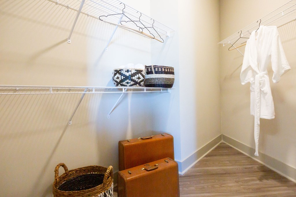 a walk in closet with luggage and a white robe