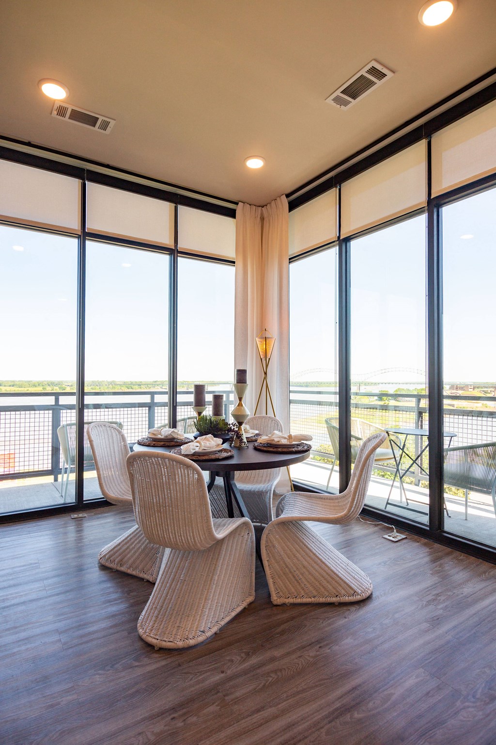 Dog-Friendly Apartments in Downtown Memphis, TN - The Landing - Dining Room with Hardwood Flooring, Round Table with Wicker Chairs, and Floor-to-Ceiling Window Walls.