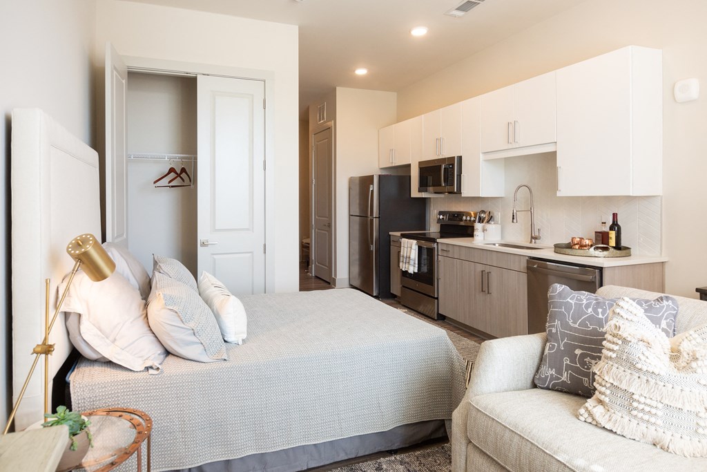 a bedroom with a bed and a kitchen