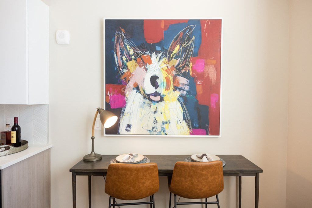 a dining room with two chairs and a painting on the wall