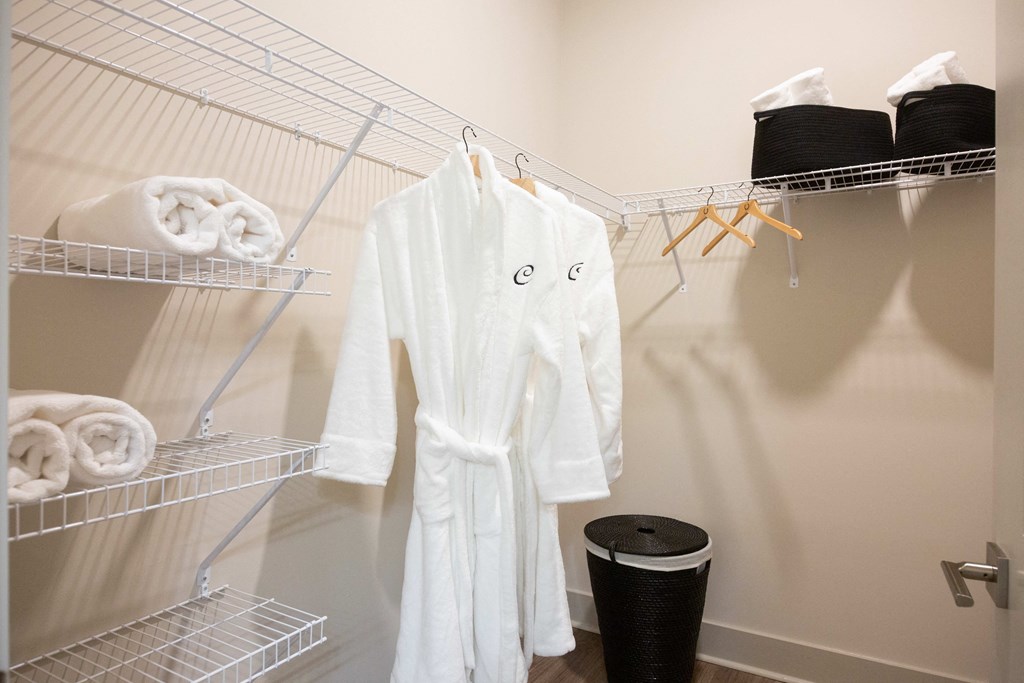 a laundry room with a white robe and a rack with towels