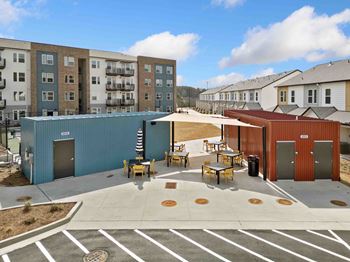 A parking lot with a blue building and a red building in the background.