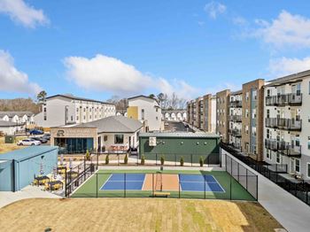 A tennis court is surrounded by apartment buildings.