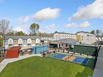 A tennis court is surrounded by a green fence and a building.