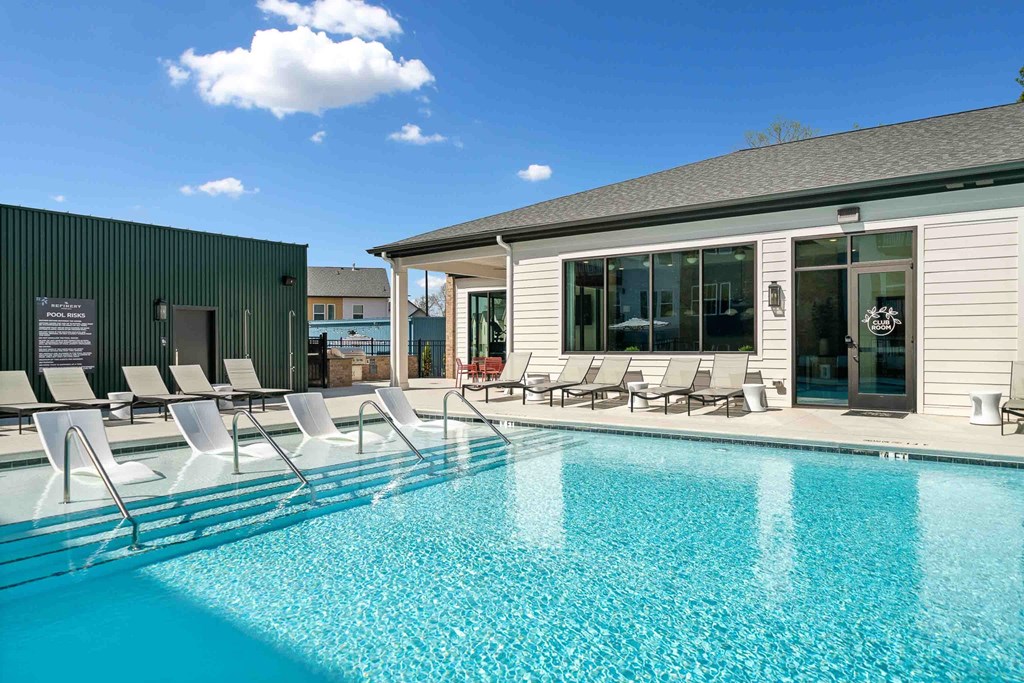 A pool with sun loungers and a building in the background.