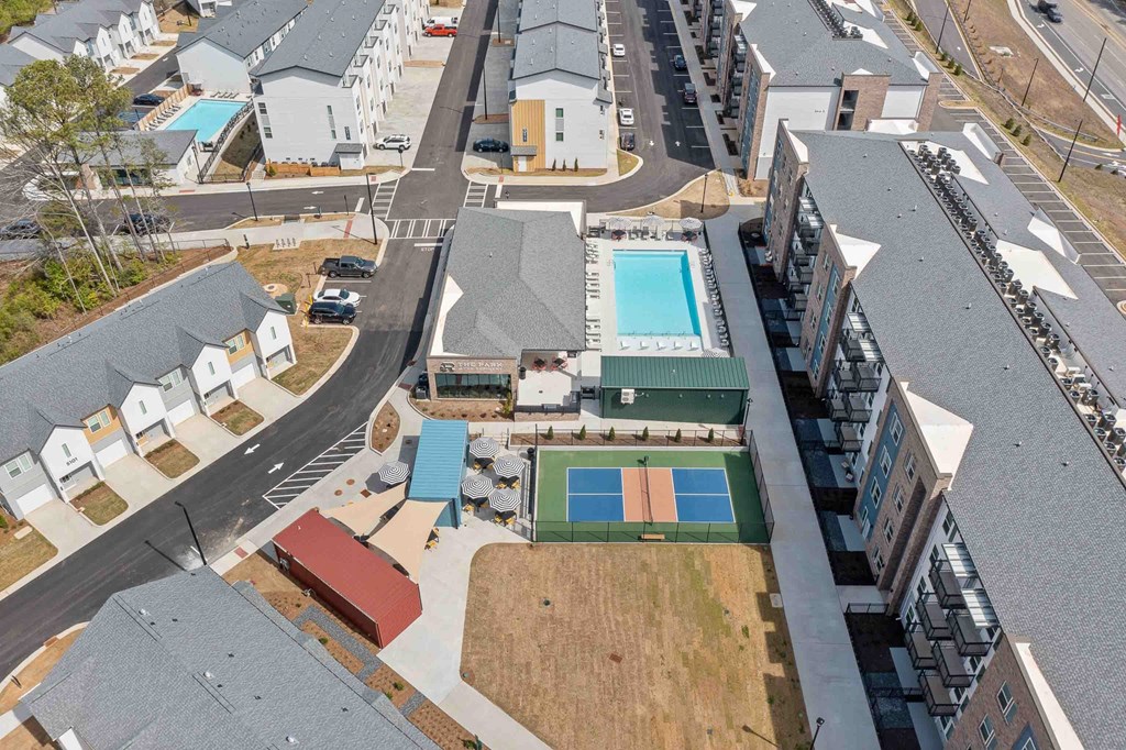 A bird's eye view of a residential area with a tennis court and a swimming pool.